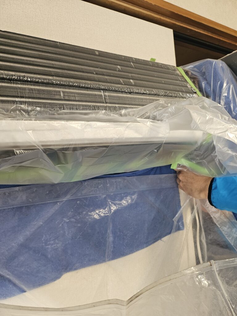 サクラクリーンワークス代表がエアコン内部を養生している画像
